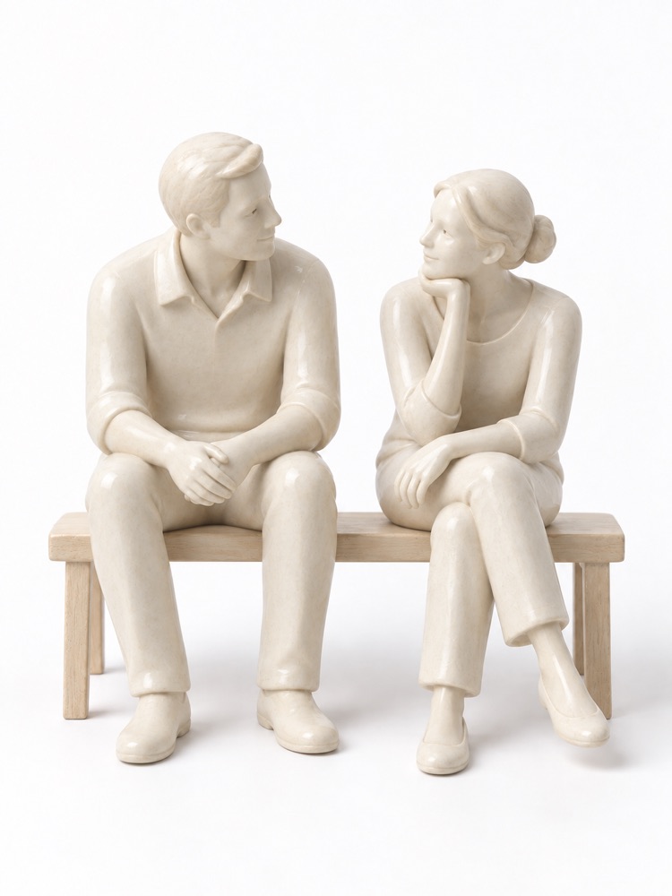 Two ivory figurines talking on a wooden bench.