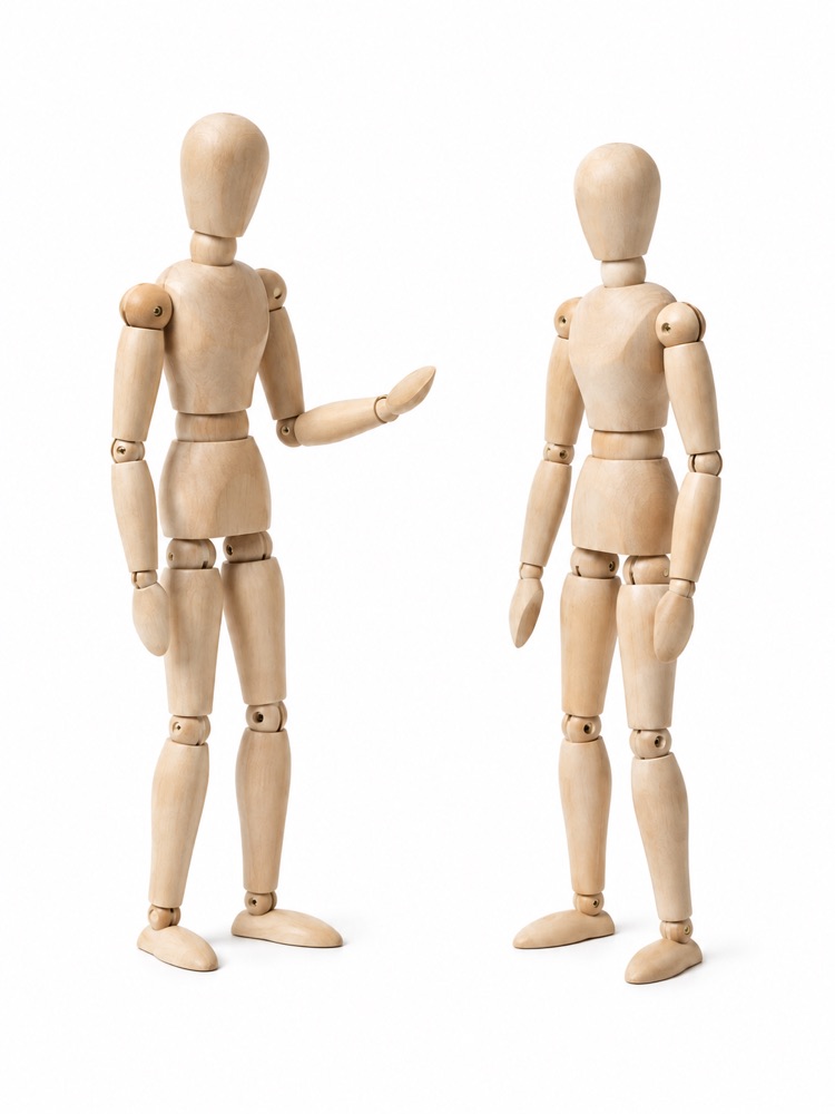 Two wooden mannequins in conversation.