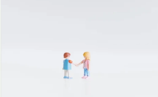 Two small toy figures standing face to face, holding hands.